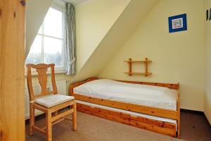 a bedroom with a bed and a chair and a window at Ostseewelle Wohnung 24 in Kühlungsborn