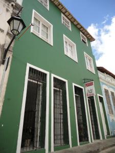 un bâtiment vert avec des fenêtres blanches sur une rue dans l'établissement Pousada Suítes Do Pelô, à Salvador