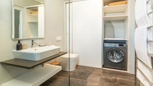 a bathroom with a sink and a washing machine at The Gallery 204 Luxury Apartment in Knysna