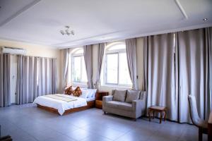 a bedroom with a bed and a chair and windows at Ivory's Nest in Accra