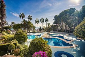 a resort pool with palm trees and purple flowers at Apartamentos Paraíso Mar in Calpe