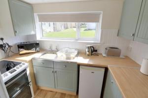a kitchen with a counter with a sink and a window at Widemouth Waves Holiday Chalet in Poundstock