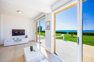 a living room with a sliding glass door to the ocean at Villa Bella Ena in Nea Dimmata
