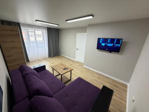 a living room with a purple couch and a flat screen tv at 2 кім кв BIG APARTMENT TOP Center in Sumy
