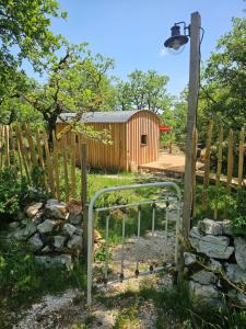 a wooden fence with a gate and a woodenshed at La nuitée belle in Cénevières