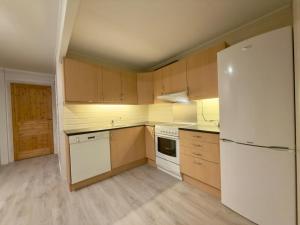 a kitchen with a white refrigerator and wooden cabinets at Smørblomstvegen Apartment in Tromsø