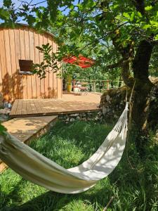 a hammock hanging from a tree in a yard at La nuitée belle in Cénevières +1 photo