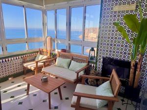 a living room with chairs and tables and windows at El Barco in Almería