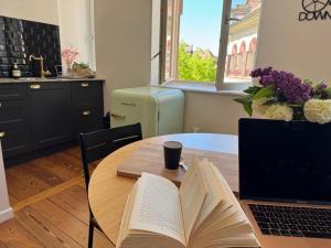 a table with a book and a laptop on it at Le Cathedral View Colmar - Centre Historique - Parking privé gratuit in Colmar