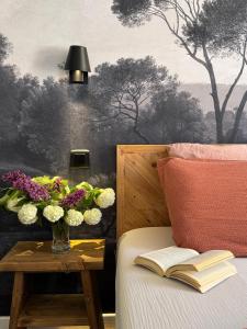 a bed with a vase of flowers and a table with a book at Le Cathedral View Colmar - Centre Historique - Parking privé gratuit in Colmar