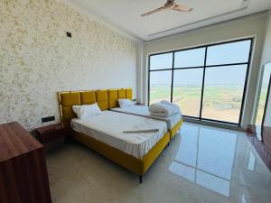 a bedroom with a bed and a large window at Hotel Picnic Garden in Patna