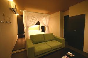 a bedroom with a green couch and a bed at Hotel VILLA ANNEX盛岡 in Morioka