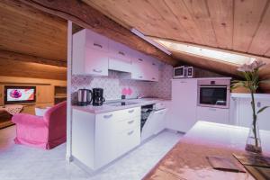 a kitchen with white appliances and a pink chair at Mansardalpina in Livigno