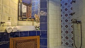 ein blau gefliestes Badezimmer mit Waschbecken und Spiegel in der Unterkunft Roes Suites in Kato Loutraki + 67 Fotos