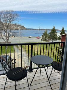 a table and chairs on a deck with a view of the water at Cupids Guest House and SheShed in Brigus
