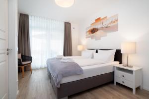 a bedroom with a large white bed and a window at Südkap B-07 in Pelzerhaken