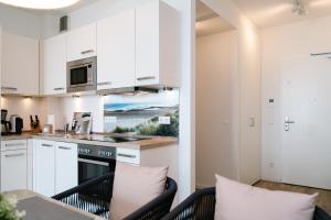 a kitchen with white cabinets and a table with pillows at Südkap B-07 in Pelzerhaken