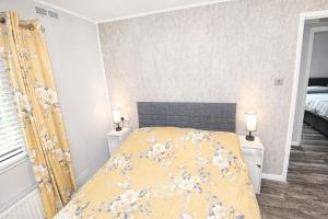 a bedroom with a bed with a yellow blanket at Grasmere 12, White Cross Bay, Windermere in Troutbeck Bridge