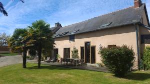 a house with a palm tree and a patio at La Peuterne in Mouazé