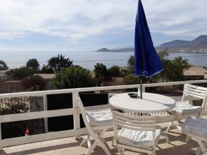 a table and chairs with a blue umbrella on a balcony at Tongoy península in Coquimbo