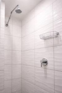 a white tiled shower with a basket on the wall at Jacuzzi Loft in the Center of Riga in Riga +14 photos
