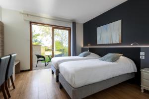 two beds in a room with a large window at Hôtel Le Mas del Pechs - Chambres avec terrasse in Sarlat-la-Canéda +64 photos