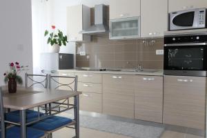 a kitchen with wooden cabinets and a table with chairs at V Apartment in Rabac