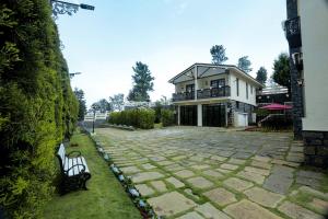 a building with a bench in front of a yard at Lynton Resorts in Kotagiri