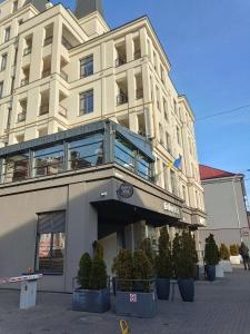 a large white building with potted trees in front of it at Апартаменти в ЦЕНТРІ ІМПЕРІАЛ in Truskavets