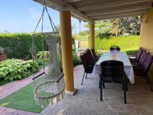 a table and chairs on a patio with a swing at La Dolche Villa in Szőlősgyörök