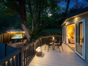 a wooden deck with a table and chairs on it at Aberdunant Hall Holiday Park, Snowdonia in Porthmadog