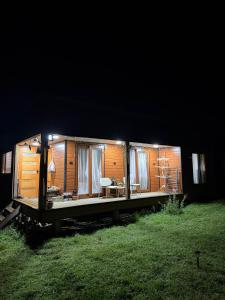 a small cabin with lights in the grass at night at Cabaña de campo in Castro
