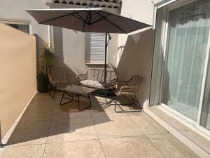 a patio with a table and chairs and an umbrella at Chambre d hôtes Cabries Calas 5 min gare TGV Aix Pôle d activités d Aix en Provence et Arena in Cabriès