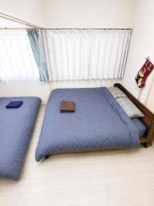 a bedroom with two beds with blue sheets and a window at 75m2 10people private house rental 8beds 8min Ikebukuro 13min Shinjuku 18min Shibuya Englishspeaking staff available in Tokyo