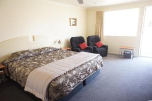 a hotel room with a bed and two chairs at Bks Egmont Motor Lodge in New Plymouth