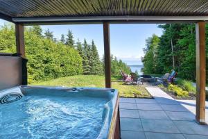 a hot tub on a patio with a view of the ocean at Käbane Kozya - La Rassembleuse in Les Éboulements