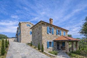 an exterior view of a stone house with blue windows at Deluxe Nature Resort Galovi Dvori in Rab