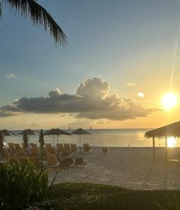 a beach with chairs and umbrellas in the sunset at Apartment with Exclusive Amenities in George Town