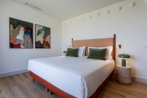a bedroom with a large white bed with green pillows at Casa Falcão Boutique Hotel by Aspasios in Porto