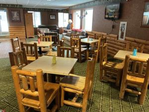 a restaurant with wooden tables and chairs in a room at Pellston Lodge in Pellston