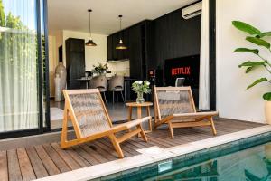 two chairs and a table next to a swimming pool at Premier Umalas Villas in Seminyak