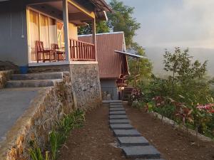 a house with a porch and a stone wall at Diva sunset garden in Senaru
