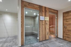 a glass door in a room with a walk in shower at Hotel Sonnenhügel, inklusive SommerCard in Filzmoos +42 photos