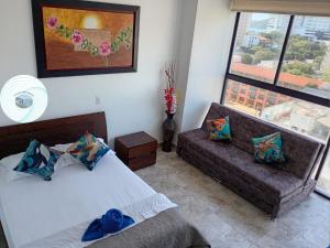 a bedroom with a bed and a couch and a window at Apartamento en el Rodadero, a pocos metros de la playa in Gaira