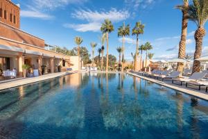 a large swimming pool with palm trees and lounge chairs at Kenzi Azghor in Ouarzazate