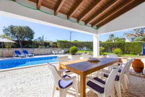 a patio with a wooden table and chairs and a pool at Vila Fantastica in Aljezur