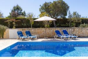 a group of chairs and an umbrella next to a pool at Vila Fantastica in Aljezur