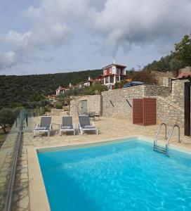 a swimming pool with chairs and a house in the background at Apollo Romantic Sea View Villa in Kiveri