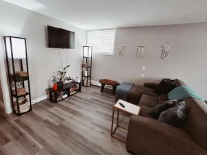 a living room with a brown couch and a flat screen tv at Riverfront Condo - Free Parking, Walk DT, Sleep 4 in Calgary