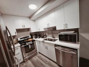 a kitchen with white cabinets and stainless steel appliances at Riverfront Condo - Free Parking, Walk DT, Sleep 4 in Calgary +9 photos